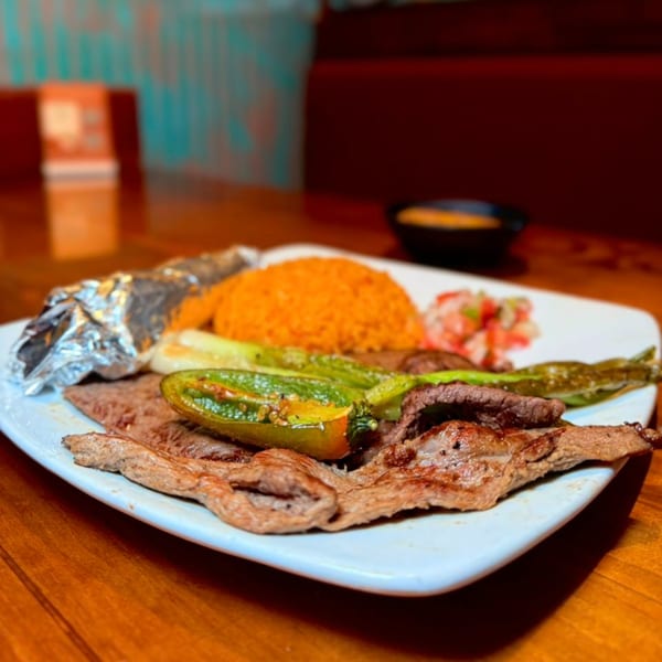 Grilled steak with rice, peppers, and salsa on a white plate at Chaparral Mexican Restaurant.