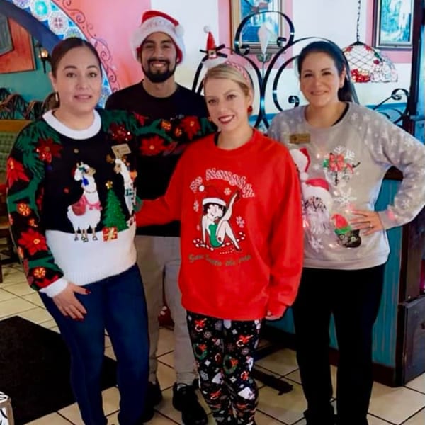 Four Chaparral Mexican and Cuban Restaurant staff members in festive Christmas sweaters pose together.